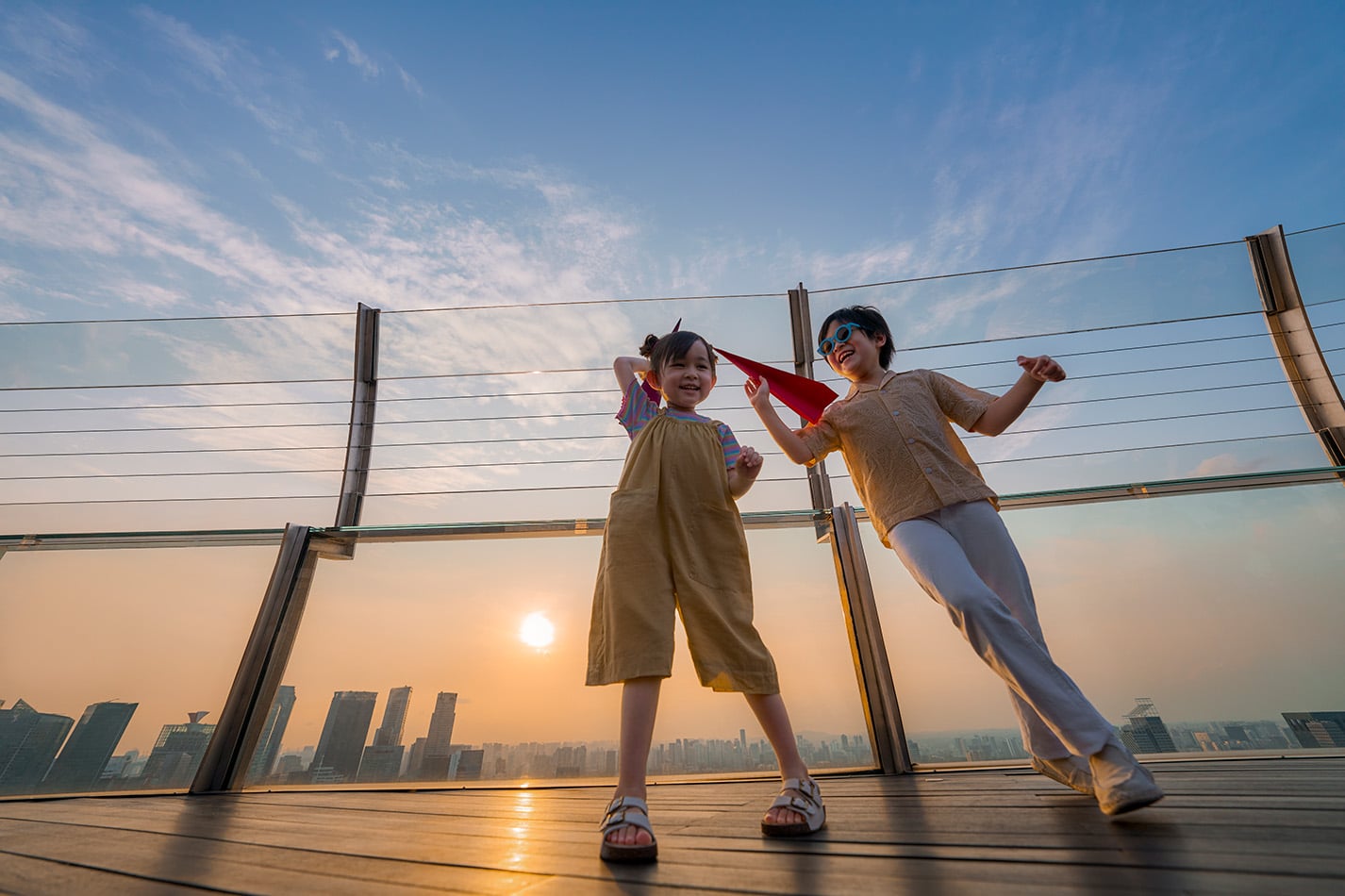 Children playing and enjoying sunset views from the SkyPark Observation Deck at Marina Bay Sands, overlooking the Singapore skyline.