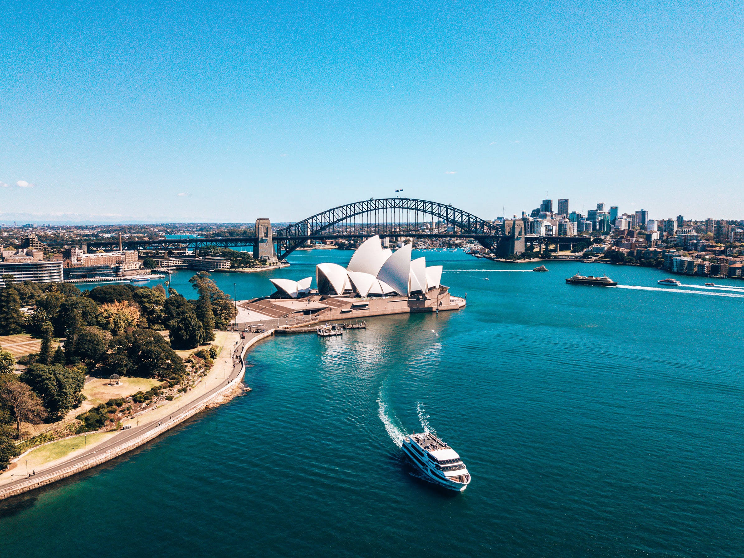 Aerial view of Sydney Harbour featuring the iconic Sydney Opera House and Sydney Harbour Bridge, bathed in golden sunset light. This quintessential Australia skyline captures the architectural grandeur and natural beauty of one of the world's most photographed urban landscapes — ideal for travel and tourism content about Sydney, New South Wales.