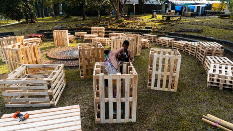 Two staff members working on one of Sunda's sets with wooden pallets.