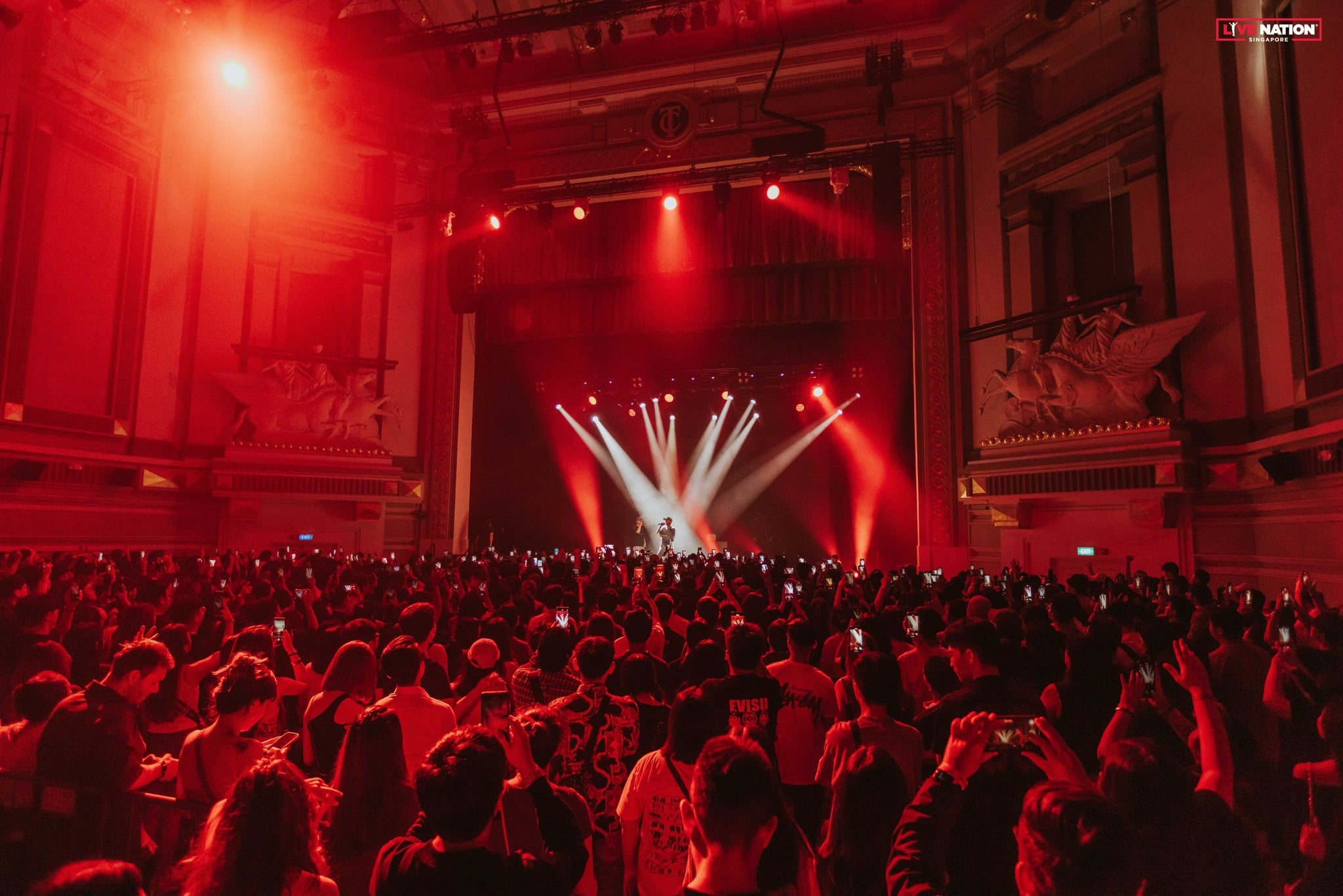 Crowd at Capitol Theatre during HALO’s F1 Singapore 2025 afterparty, with dramatic red lighting and live DJ performance on stage.
