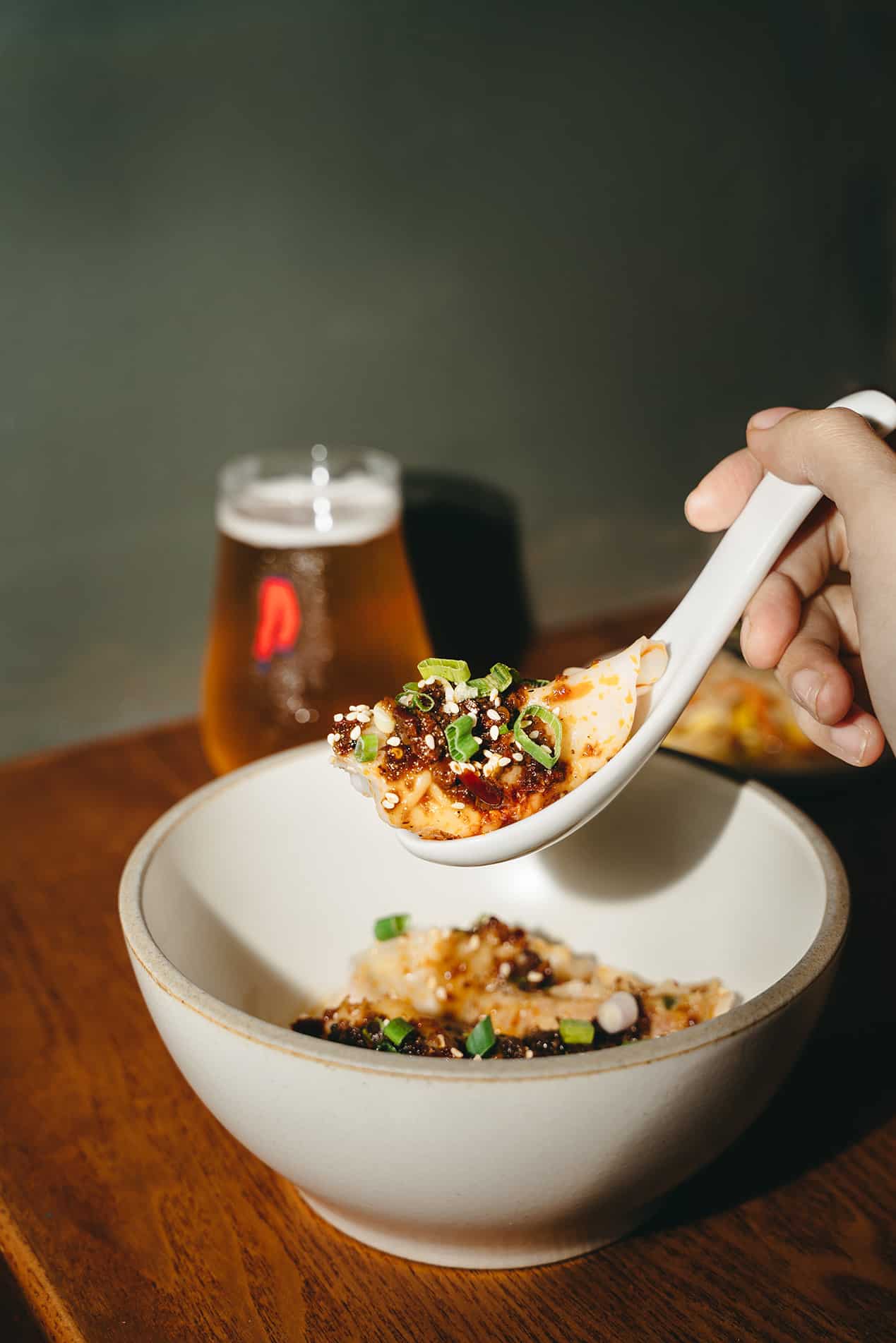 Close-up of dumplings with Szechuan sauce and craft beer at Dumpling Darlings, a casual happy hour spot in Singapore.