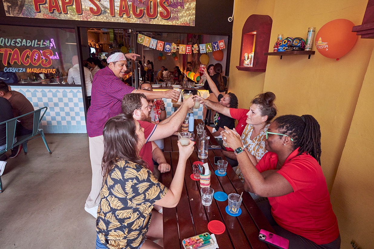 Group of friends toasting margaritas at Papi’s Tacos during happy hour, a lively Mexican eatery in Singapore.