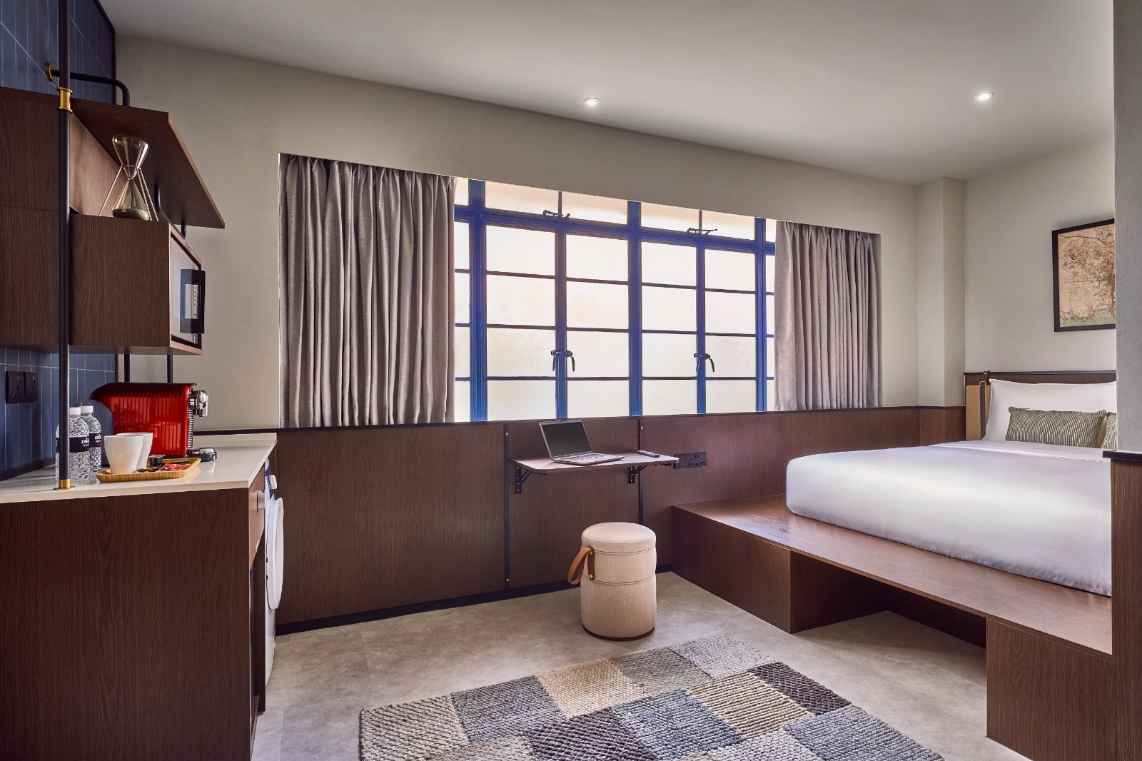 Stylish room at Coliwoo Hotel Kampong Glam Singapore, with natural light, work desk, queen bed, and kitchenette for long stays