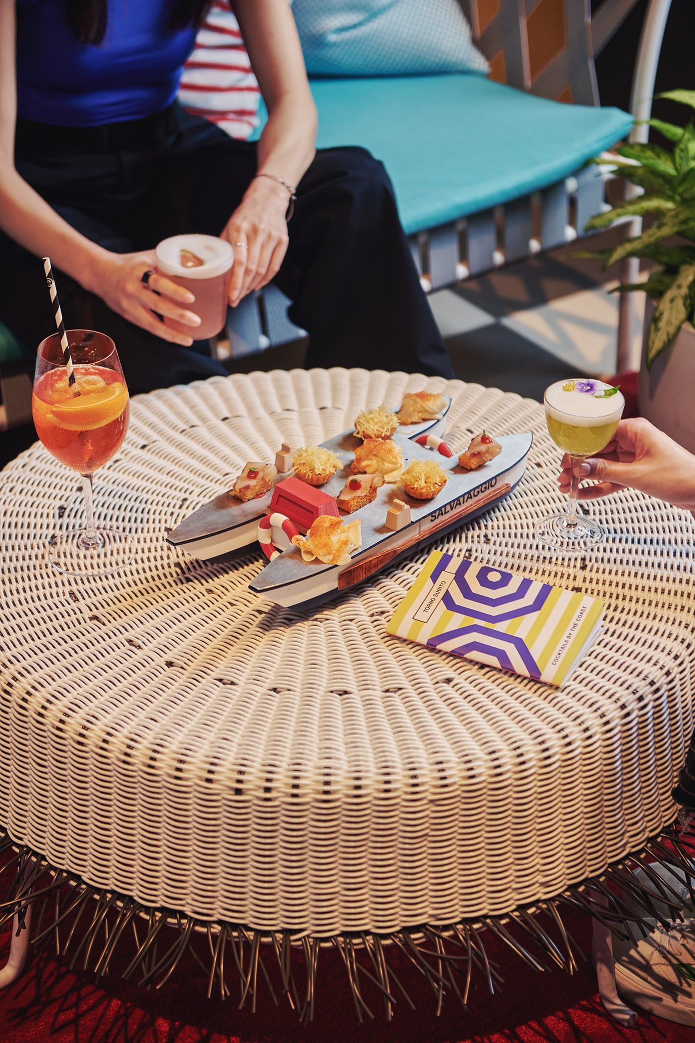 Colourful cocktails and bar snacks served on a boat-shaped platter at Torno Subito’s AperiTorno happy hour in Singapore.